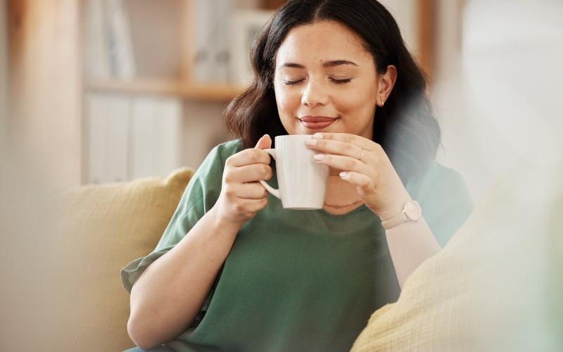 a woman drinking from a cup sitting on a couch